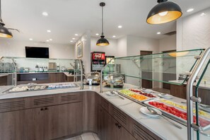 A buffet area with a variety of food options, a Coca-Cola refrigerator, and a glass railing.