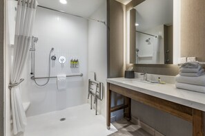 Enjoy a refreshing shower in the bathroom, featuring a walk-in shower with a glass door, vanity with a large mirror, and a bathtub.