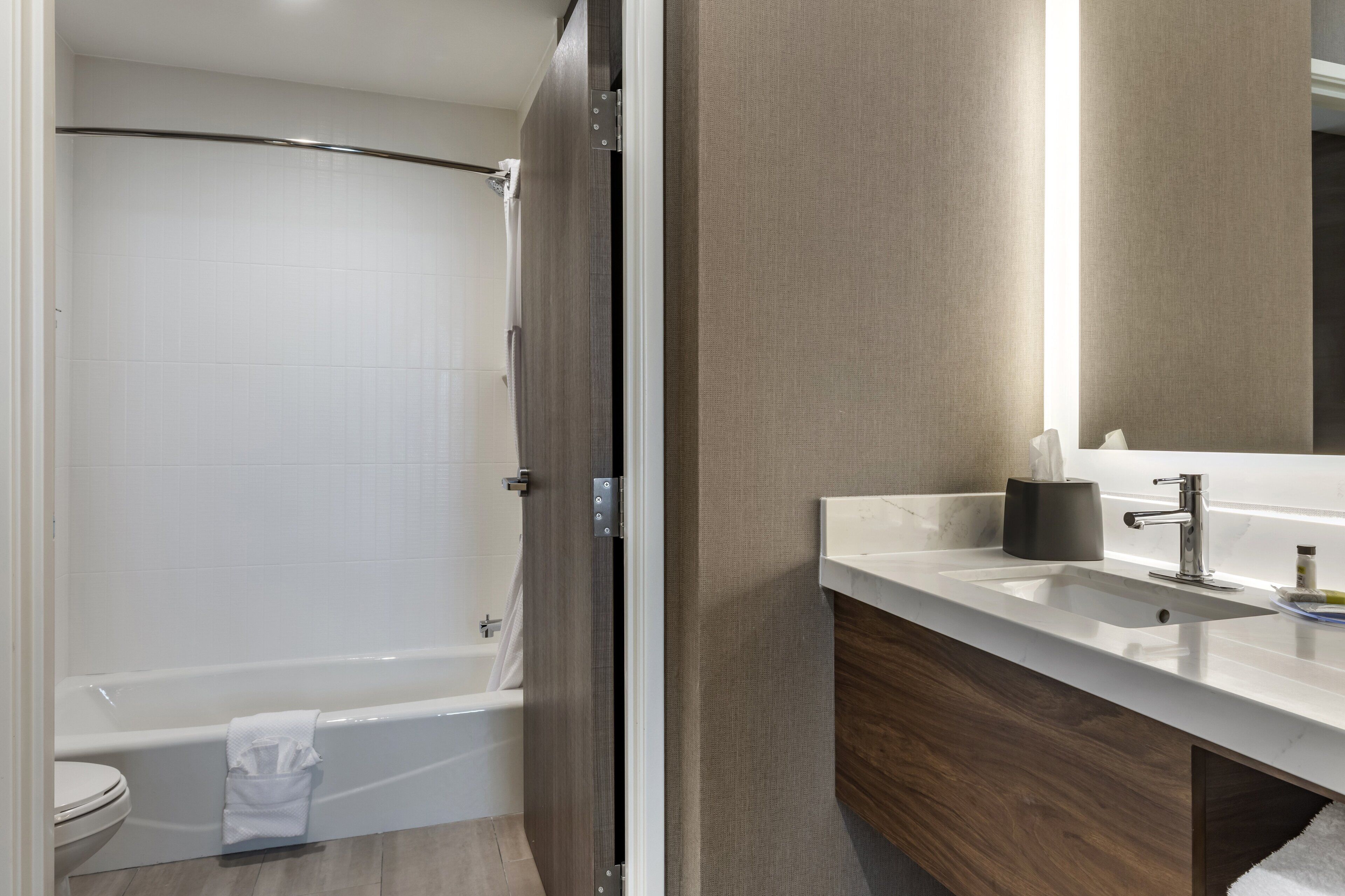 Une salle de bain moderne équipée d’une baignoire, de toilettes et d’un meuble-lavabo avec un miroir.