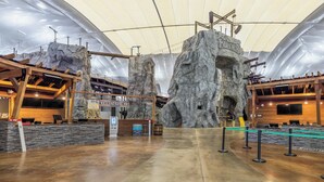 Un vaste espace intérieur doté d’un haut plafond, de poutres en bois et d’une grande structure rocheuse portant l’inscription « Bolder ».