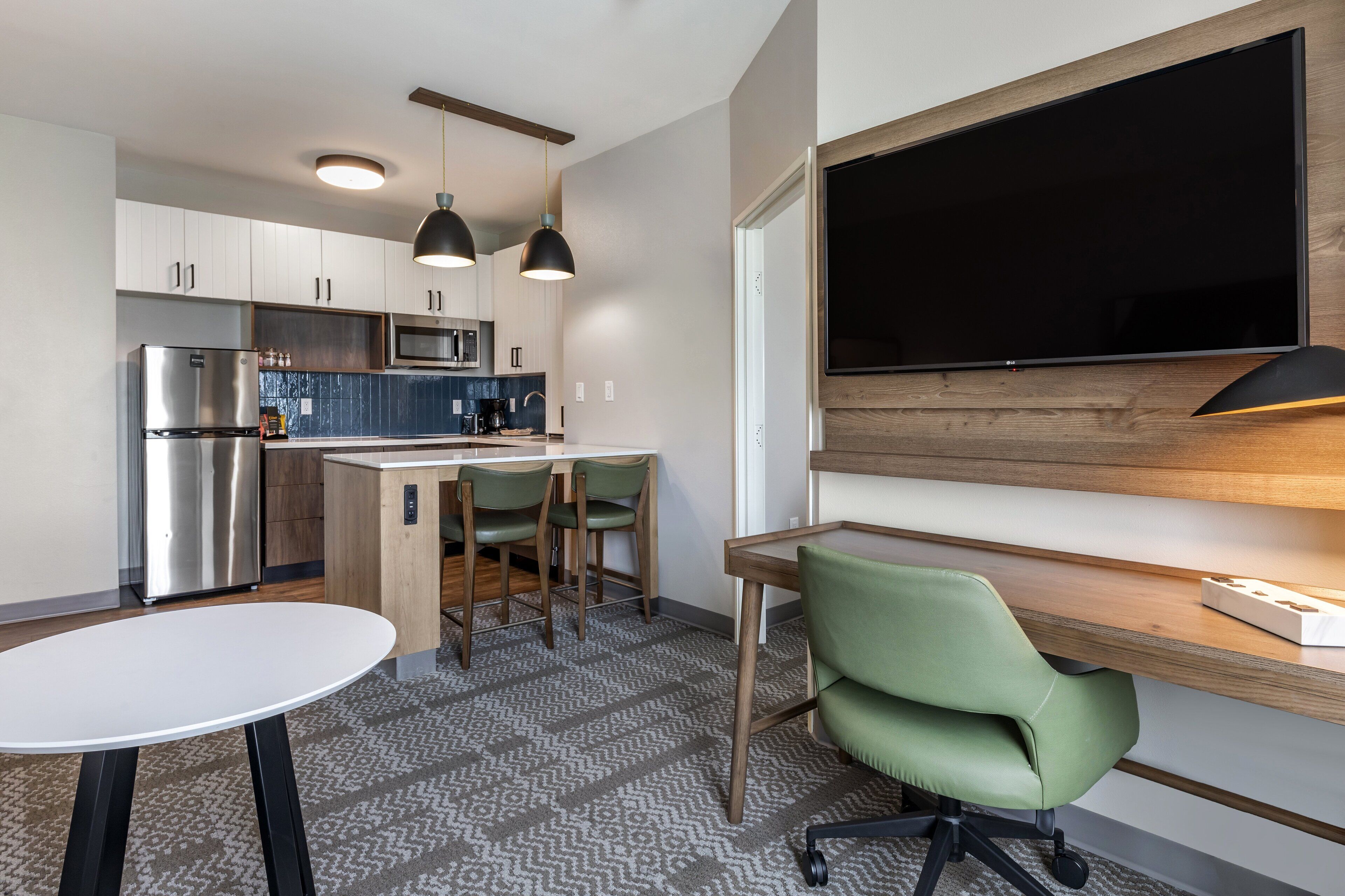 A modern kitchen with a built-in microwave, stainless steel refrigerator, and pendant lights.