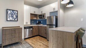 Une cuisine moderne avec des armoires blanches, des appareils en acier inoxydable et un îlot central en bois.