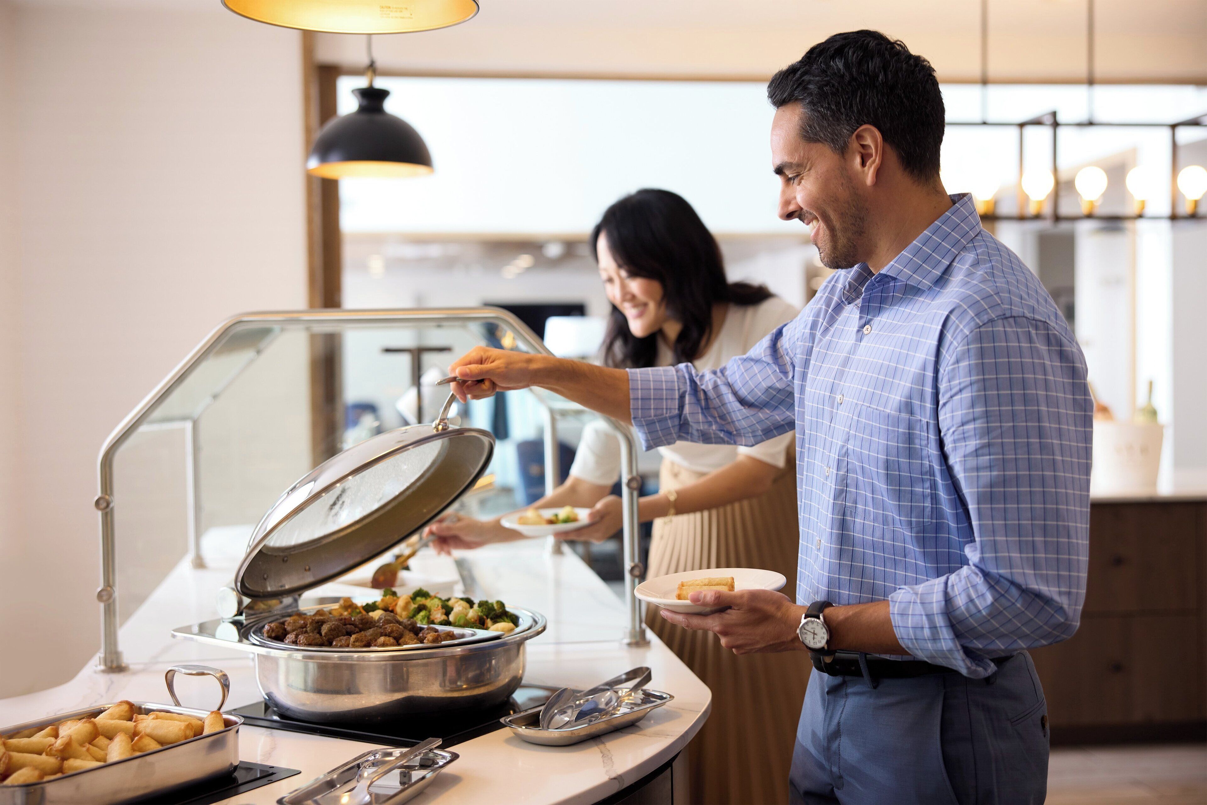 A buffet setup with various food items and a person serving food.