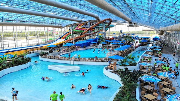 Parque aquático interno com várias piscinas, toboáguas e um escorregador gigante.
