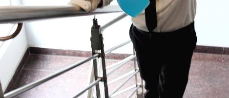 Une personne nettoie un escalier à l’aide d’un vaporisateur bleu.