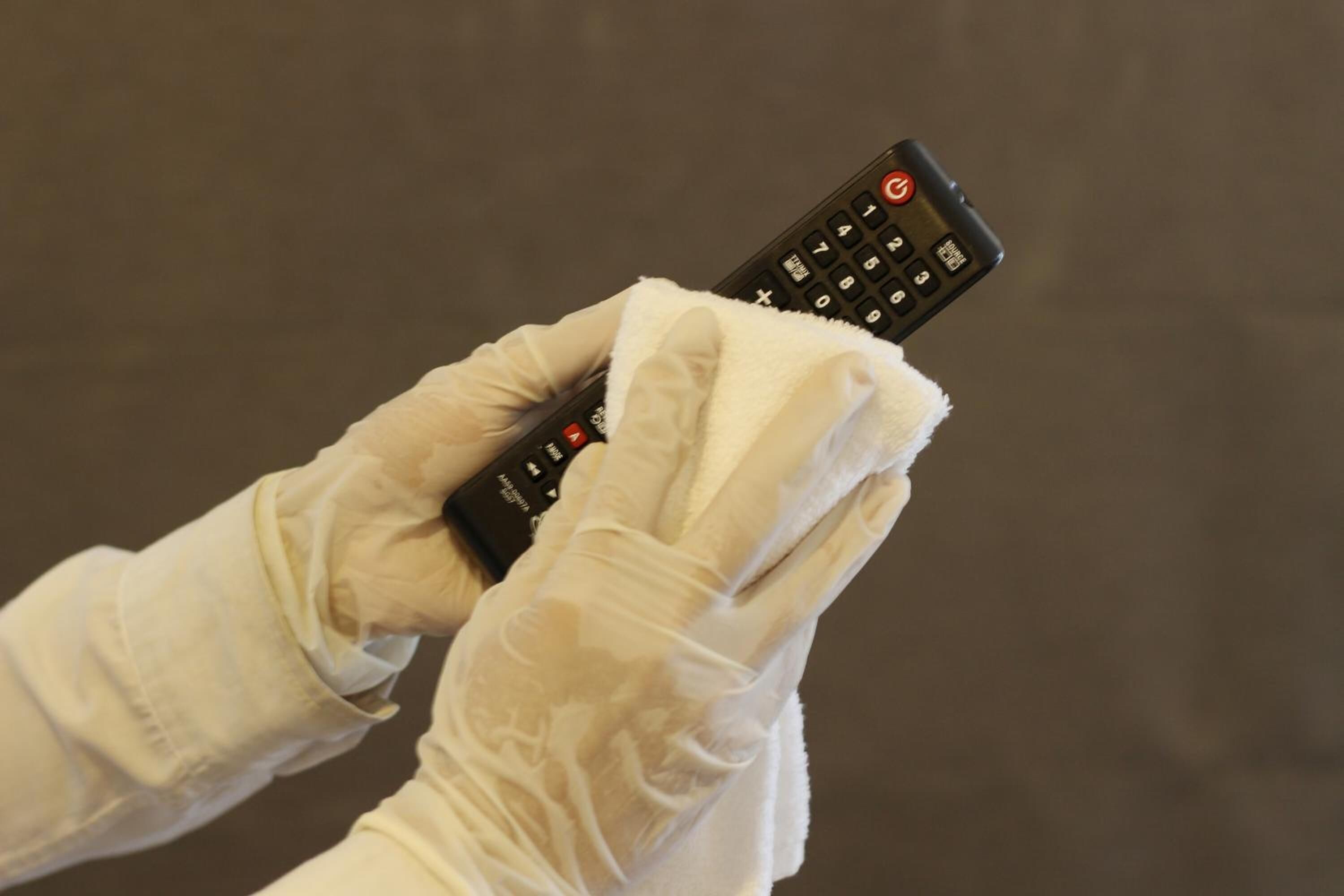 A person wearing white gloves holding a remote control.