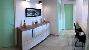 A hallway with a wooden console table, a framed photograph, and a green door.