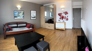 A modern living room with a wooden floor, a sofa, a table, and a mirror.