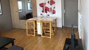 A modern living room with a wooden dining table, a TV, and a large mirror.