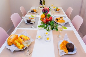 Enjoy a meal at this beautifully set table, complete with a variety of dishes, fresh fruit, and wine.