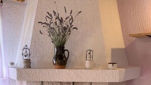 Una chimenea de piedra con arco de madera, un jarrón con plantas y dos pequeñas jaulas de pájaros sobre la repisa.