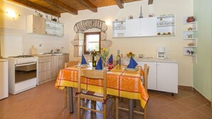 A cozy kitchen with wooden beams, a dining table set for four, and a stone archway. - Apartment Justina-Labin-quiet place (Sveta Nedelja)