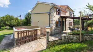 A two-story house with a stone facade, a wooden deck, and a fenced garden area. - Apartment Justina-Labin-quiet place (Sveta Nedelja)