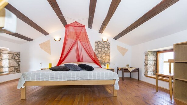 A bedroom with a bed, wooden beams, stone walls, and a window. - Apartment Justina-Labin-quiet place (Sveta Nedelja)