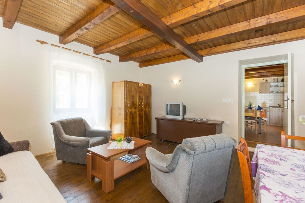 A cozy living room with wooden beams, a sofa, a coffee table, and a TV.