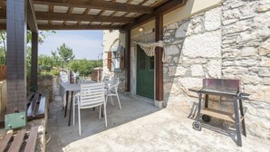 An outdoor patio with a table and chairs, a barbecue grill, and a stone wall. - Apartment Justina-Labin-quiet place (Sveta Nedelja)