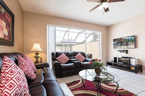 Relax in this stylish living room with a comfortable sofa, flat-screen TV, and a beautiful view of the surrounding greenery.