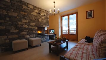 Relax in this inviting living room with a fireplace, comfortable seating, and a large window offering a balcony view.