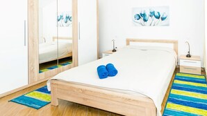A bedroom with a wooden bed, a mirror cabinet, a bedside table with a lamp, and a blue and yellow striped rug. - Apartment Janko N1 (Medulin)
