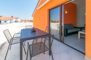 A rooftop terrace with a table and chairs, a sofa, and a sliding glass door leading to an indoor area. - Apartment Janko N1 (Medulin)