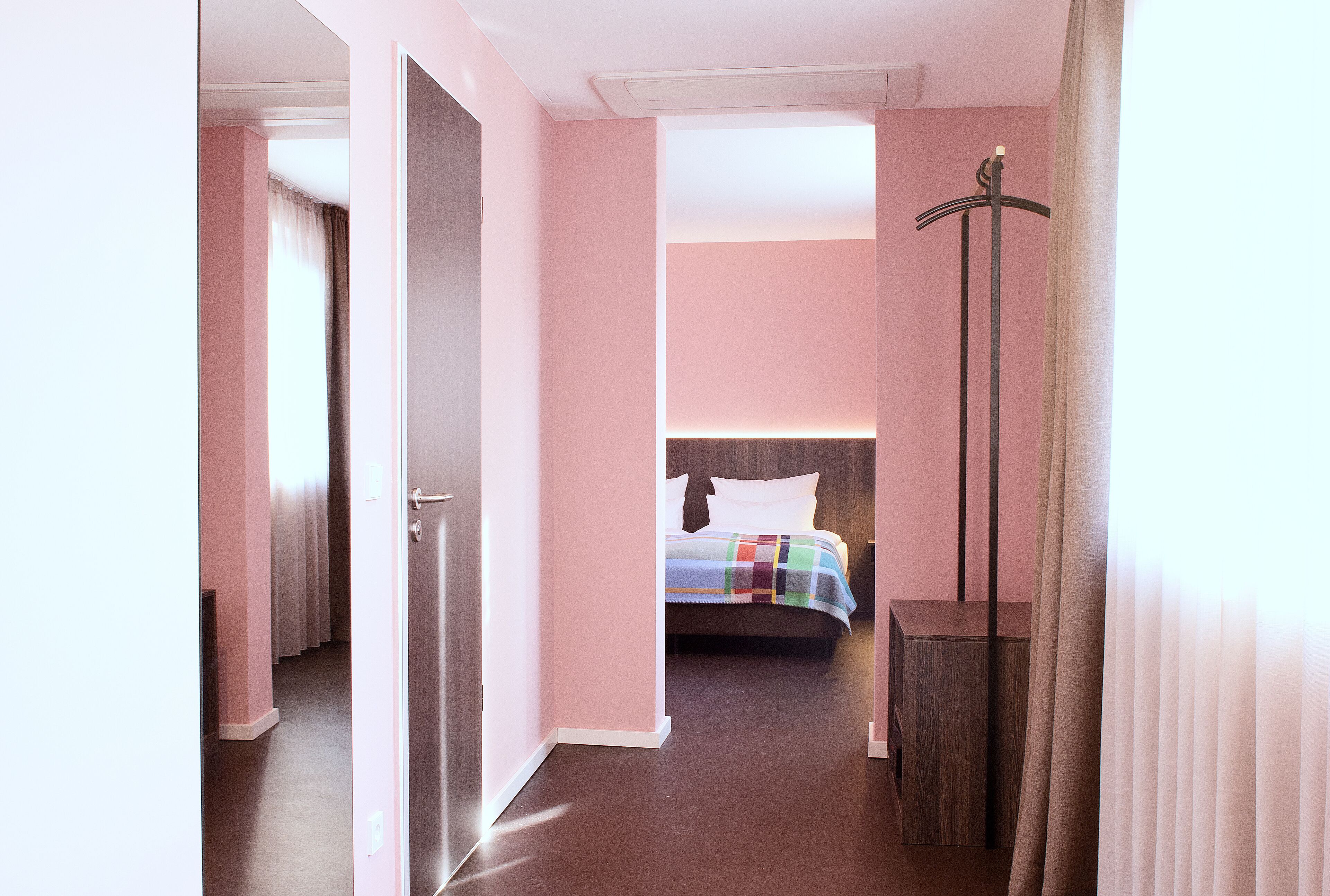 A hotel room with a bed, a bedside table, a wardrobe, and a mirror.