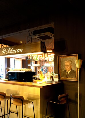 A bar area with a coffee machine, bar stools, and a framed portrait on the wall. - Central Hotel Münster (Münster)