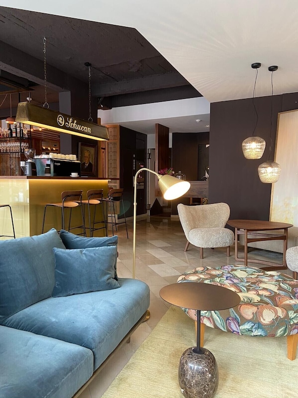Una sala de estar moderna con un sofá azul, una barra de café y una zona de comedor con mesa y sillas.