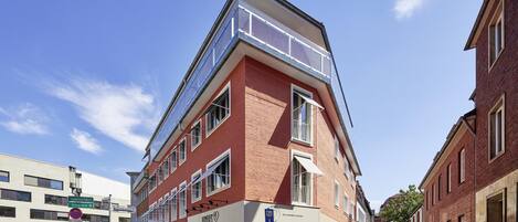 A corner building with a red brick facade, multiple windows, and a glass storefront.