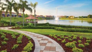 A landscaped pathway with a gazebo, a pond, and a fountain. - Encantada Resort (Kissimmee)