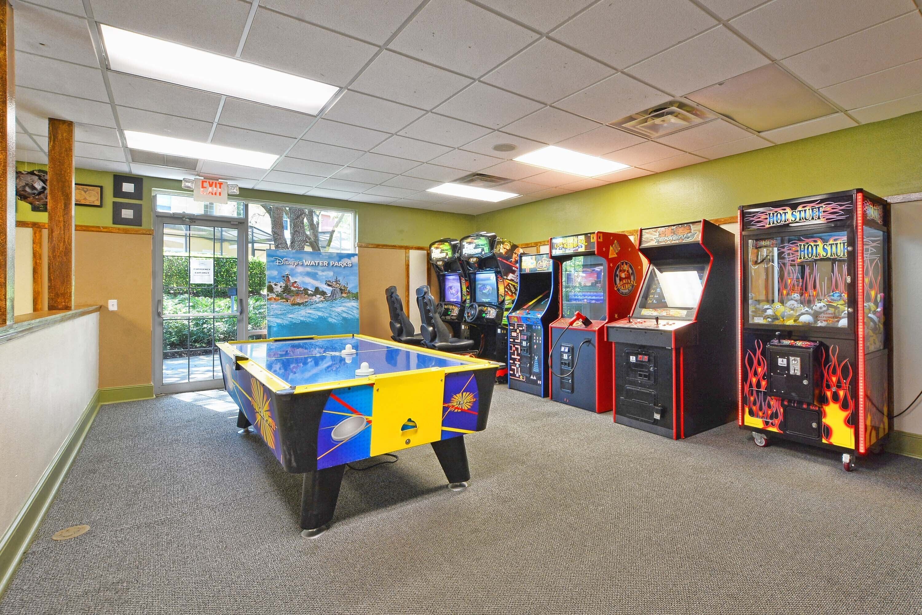 A room with a foosball table, arcade games, and a pool table.