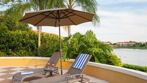 A terrace with two lounge chairs, a table with a drink, and an umbrella. - Encantada Resort (Kissimmee)