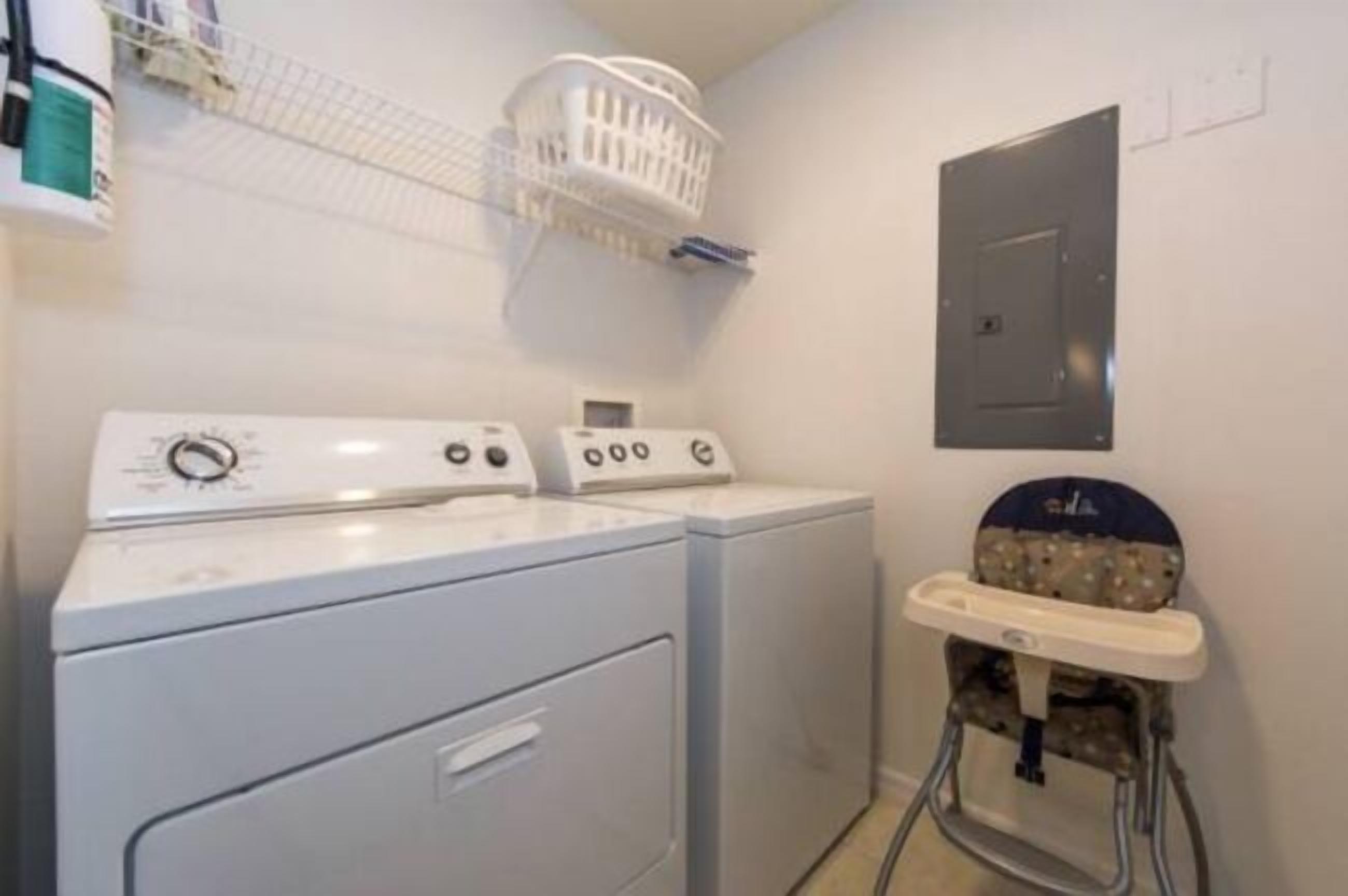 Un espace buanderie équipé d’un lave-linge, d’un sèche-linge et d’une table à langer pour bébé.