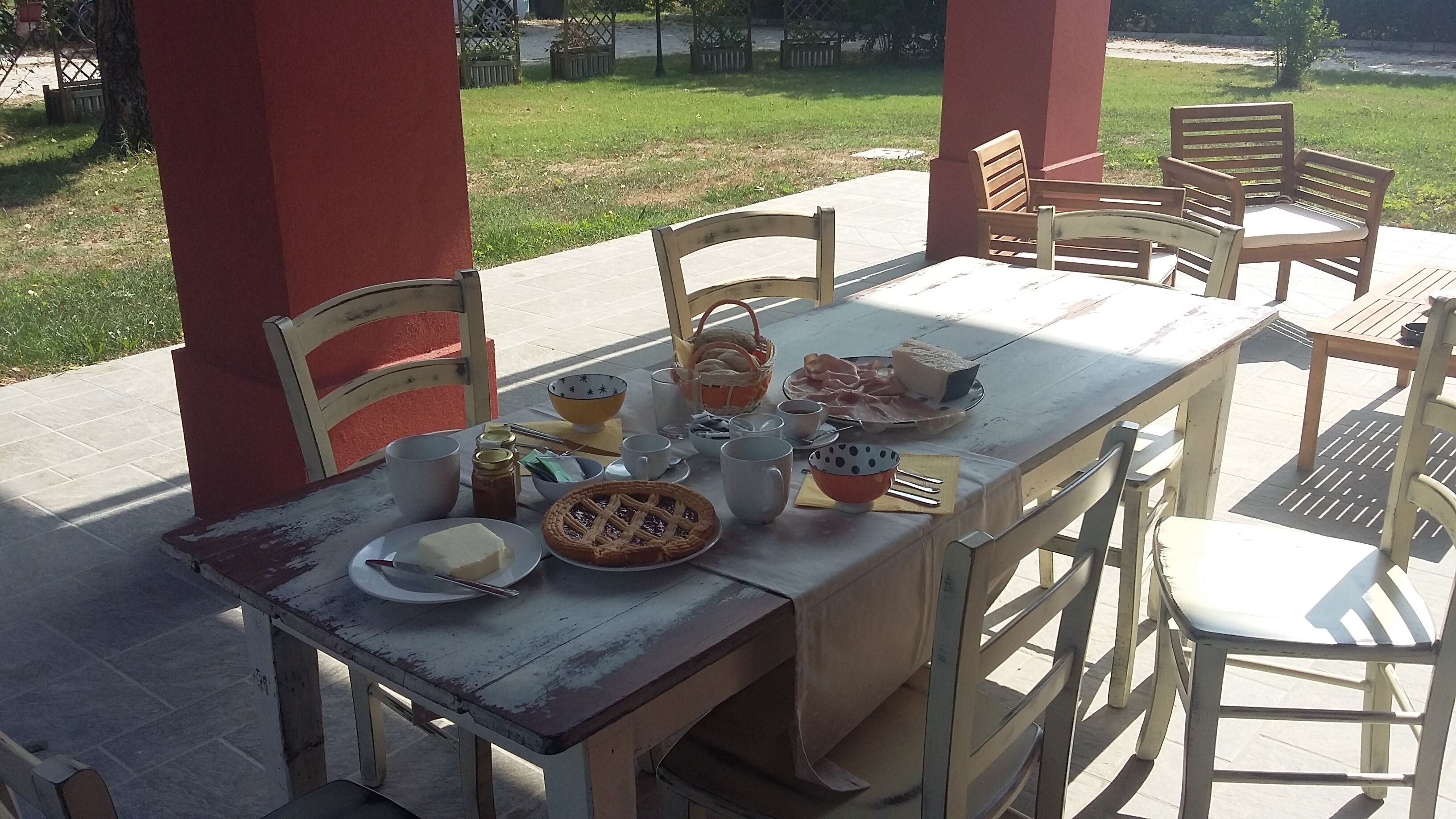 An outdoor dining area with a table set for a meal, surrounded by chairs.