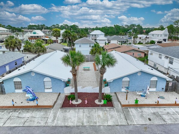 A residential area with two blue buildings, palm trees, and a playground.