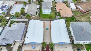 Vista aérea de una zona residencial con casas, un camino central y un estacionamiento.