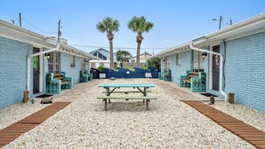 Un patio con dos palmeras, una mesa de picnic y bancos.