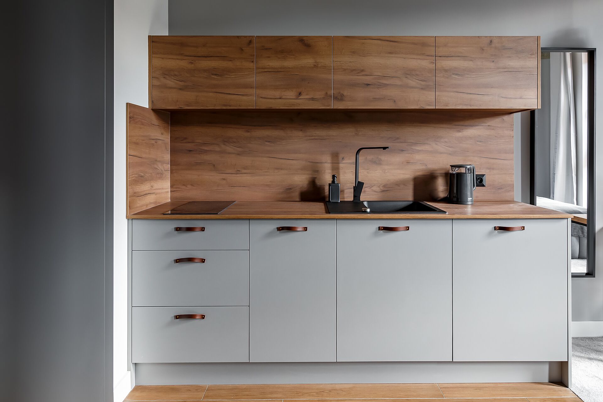 A modern kitchen with a wooden countertop, a black faucet, and a kettle.