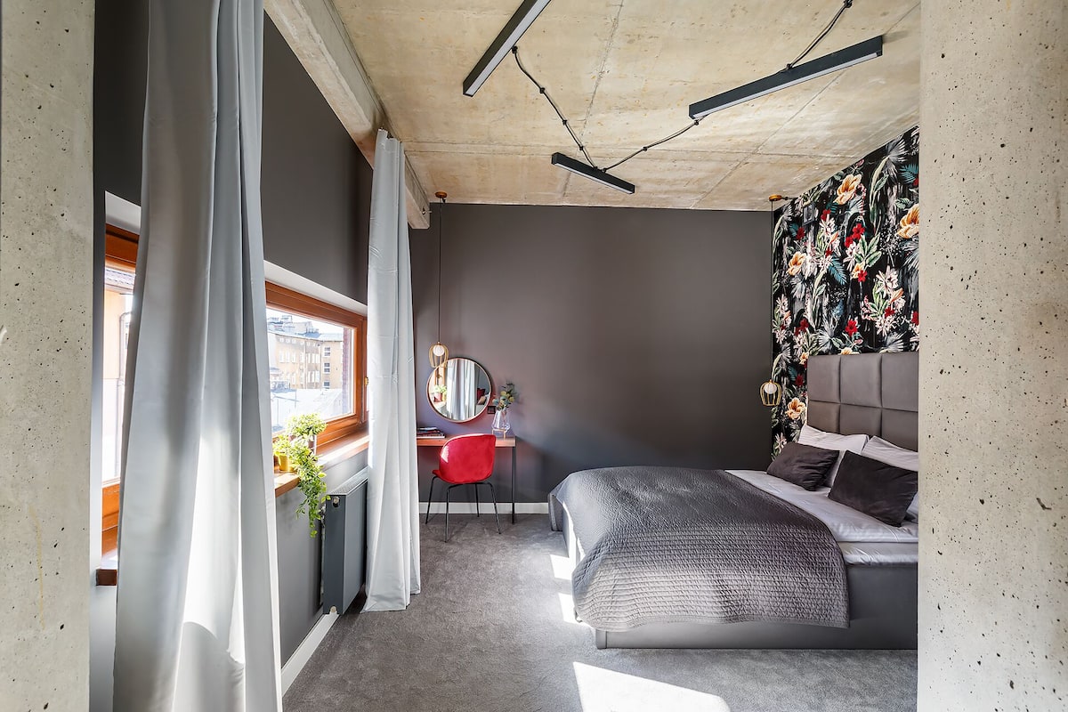Un dormitorio con cama, escritorio, silla y ventana con cortinas.