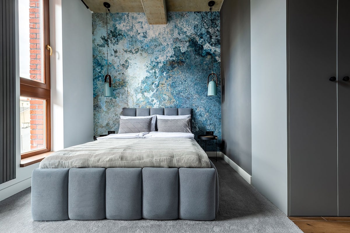Un dormitorio con cama, mesita de noche, lámpara y armario.