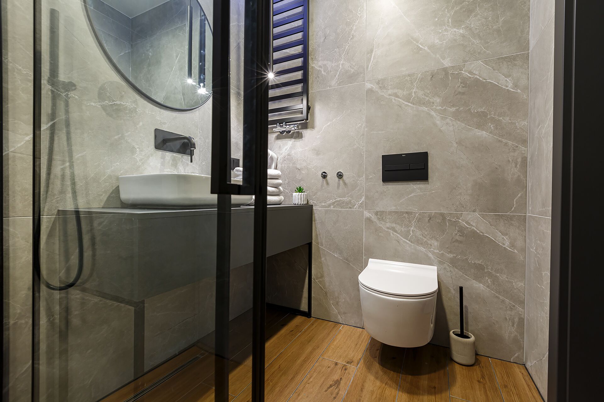 Et moderne badeværelse med et glasbadeværelse, en hvid vask og et toilet.