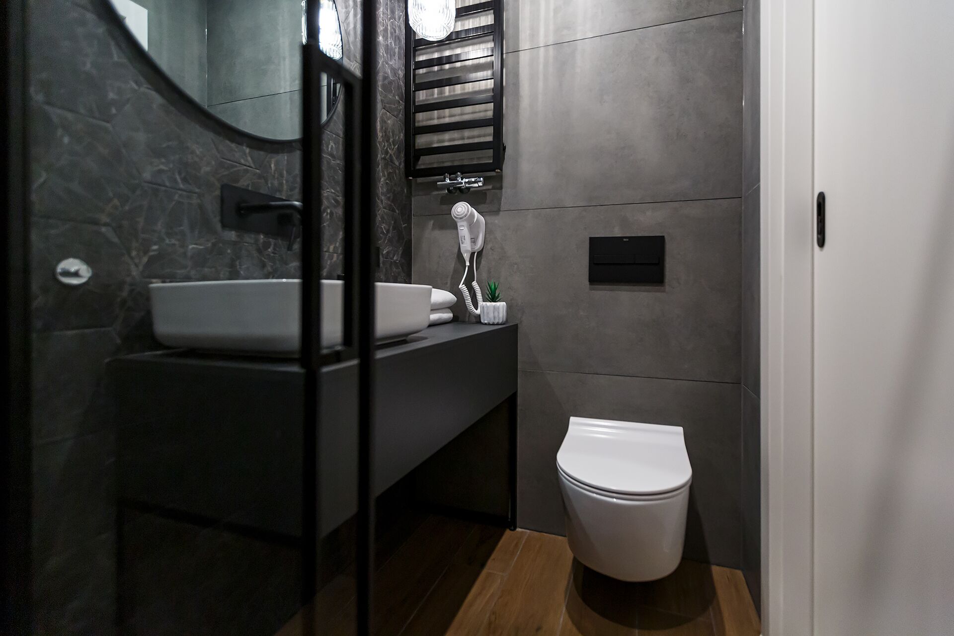 A modern bathroom with a white sink, a toilet, and a hairdryer on the wall.