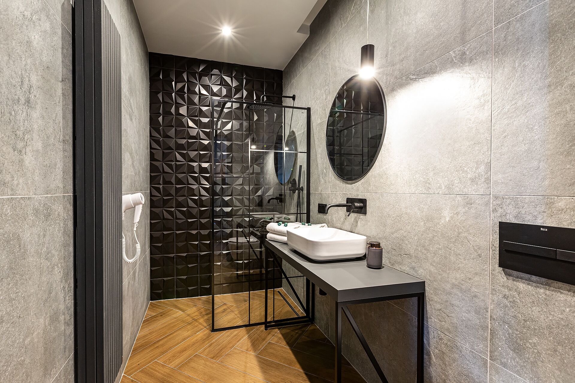 A modern bathroom with a glass shower enclosure, a white sink, and a large mirror.