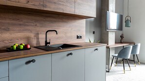 A modern kitchen with wooden cabinets, a sink, and a dining area with chairs.