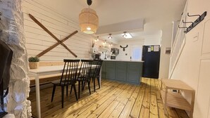 Una cocina compacta con suelo de madera, una mesa de comedor con sillas, una lámpara colgante y una isla integrada con un fregadero.