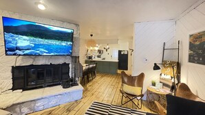 Una sala de estar acogedora con chimenea, un televisor montado en una pared con textura y piso de madera.