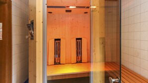 A sauna room with a glass door, wooden walls, and a bench. - Tirolerhof (St. Ulrich Am Pillersee)