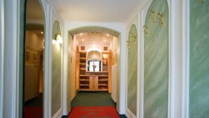 A hallway with a red carpet, wooden cabinets, and a green wall. - Tirolerhof (St. Ulrich Am Pillersee)