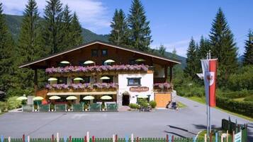 A traditional wooden building with a balcony adorned with flowers, a sign reading "Talerhof," and a flagpole with a flag.
