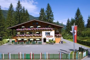 A traditional wooden building with a balcony adorned with flowers, a sign reading "Talerhof," and a flagpole with a flag. - Tirolerhof (St. Ulrich Am Pillersee)
