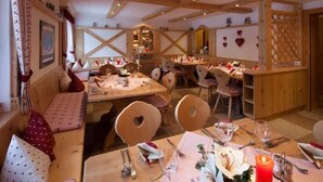 A cozy dining area with wooden furniture, heart-shaped chairs, and a table set for a meal. - Tirolerhof (St. Ulrich Am Pillersee)
